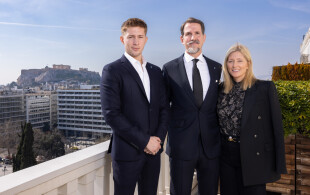 Le prince Pavlos de Grèce entouré de son fils aîné, le diadoque Constantin, et de son épouse, la princesse Marie-Chantal, avec en arrière-plan, l’Acropole d’Athènes.