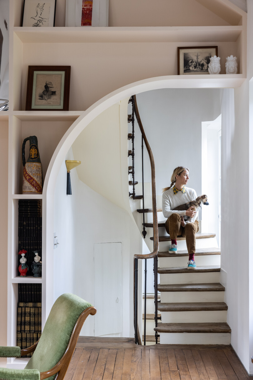 Victoire de Pourtalès pose dans l'escalier de sa maison avec son chien, Jackie.