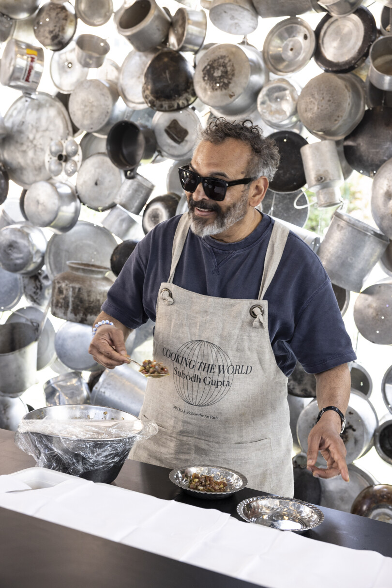 L'artiste plasticien Subodh Gupta réalise sa performance artistico-culinaire Cooking The World.