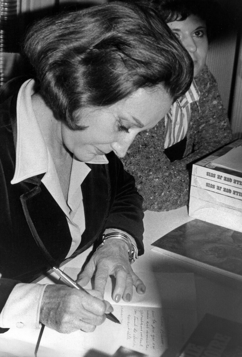 En plus de son émission radiophonique, Menie Grégoire publie plusieurs ouvrages dont une autobiographie Telle que je suis. La journaliste est photographiée ici lors d'une séance de dédicaces à Paris, le 6 décembre 1976.