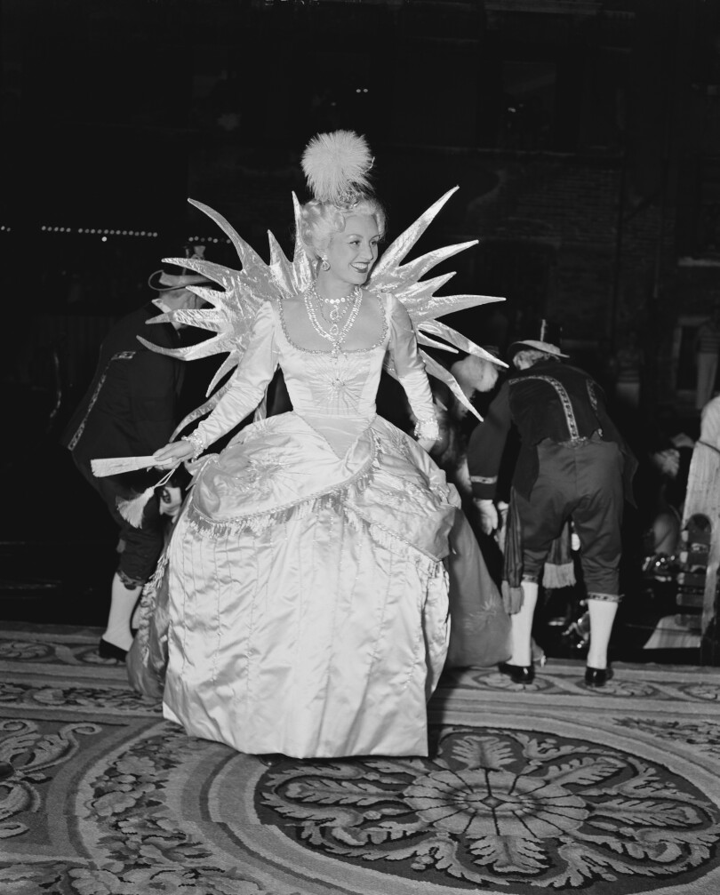 Geneviève Fath, épouse du couturier français Geneviève Fath, arrive au Bal du Siècle...
                                        <div id=